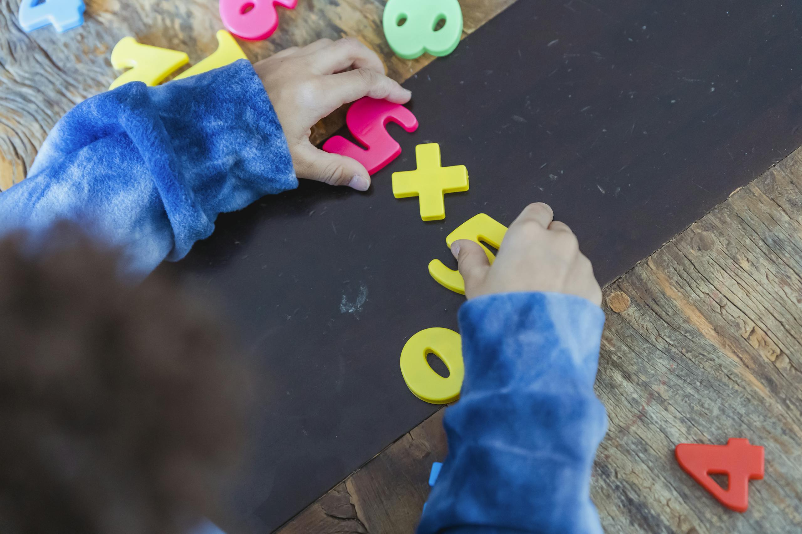 Ethnic boy solving mathematical example made of toy numbers