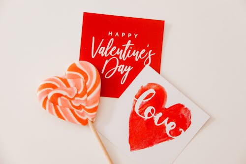 Heart-shaped lollipop and Valentine's Day cards in a flatlay for love theme.